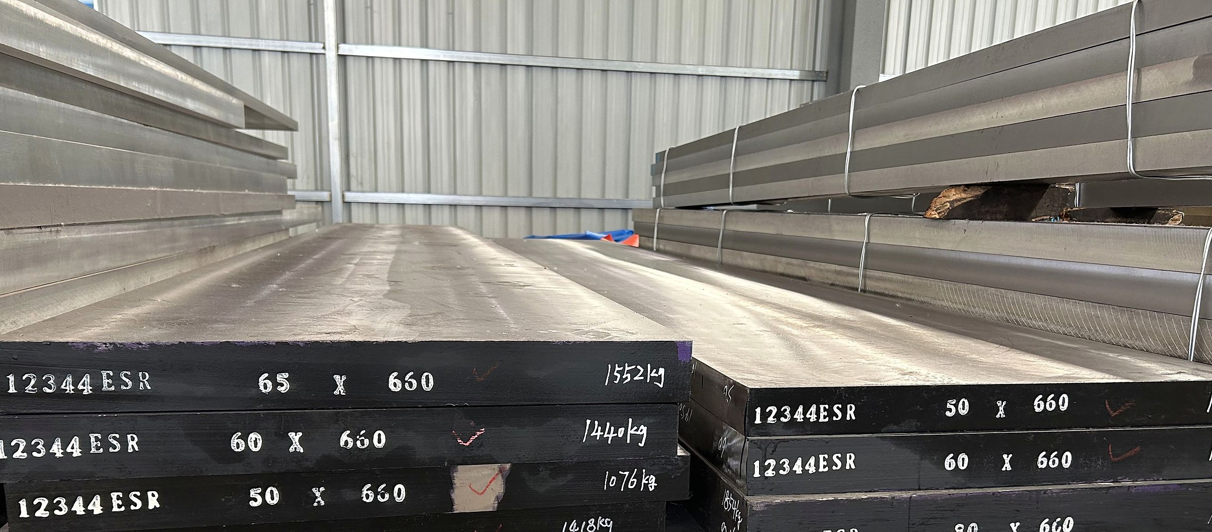 1.2344 ESR die steel plates stacked in a warehouse, plate ends painted 12344 ESR with the section size and weight